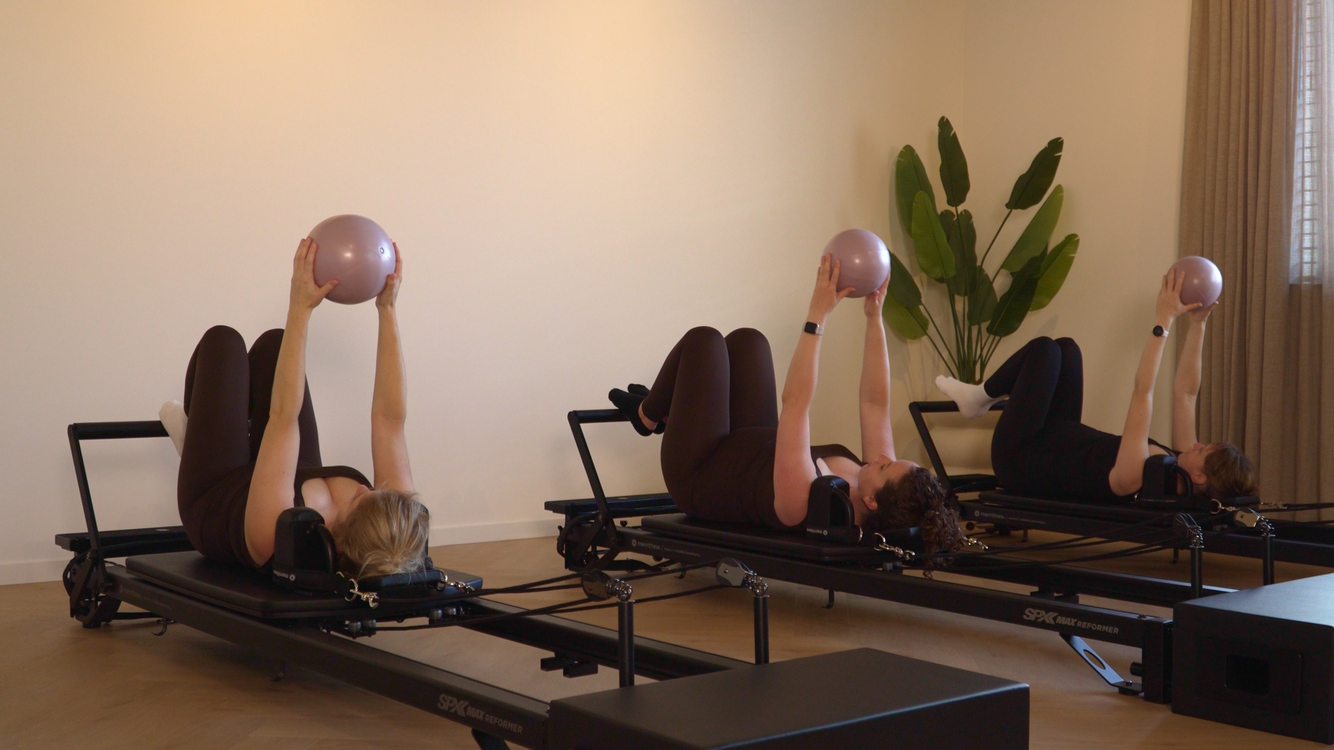 groep vrouwen op reformers in pilates houding met een bal 